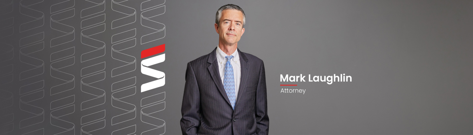Mark Laughlin, Fraser Stryker attorney, wearing a dark blue suit jacket, dark blue pants, white shirt and light blue patterned tie. Fraser Stryker logo icon repeating on the left side of the photo.