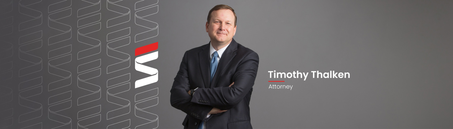 Timothy Thalken, Fraser Stryker attorney, wearing a dark blue suit jacket, dark blue pants, white shirt and light blue patterned tie. Fraser Stryker logo icon repeating on the left side of the photo.