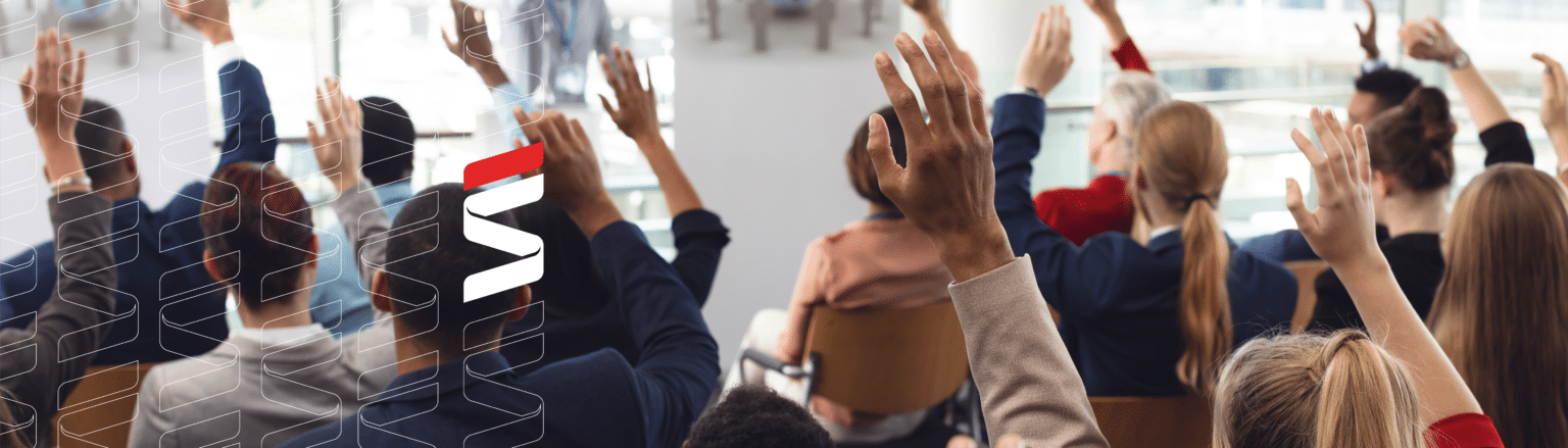 People raising hands in a professional seminar setting. Fraser Stryker logo icon repeating on the left side of the photo.