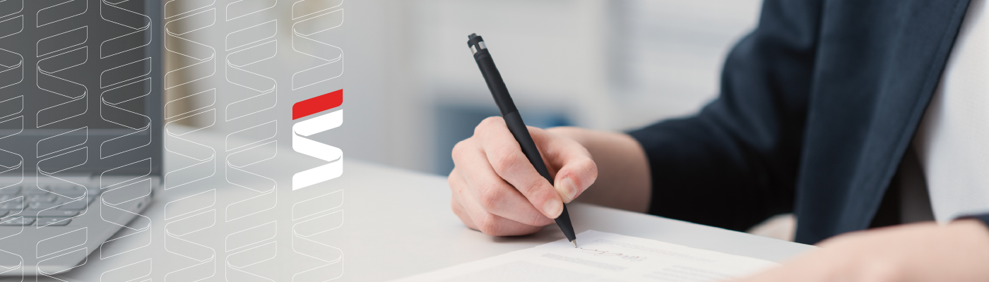 A person in formal attire signing a document with a pen on a desk, with a laptop nearby and the Fraser Stryker logo on the side