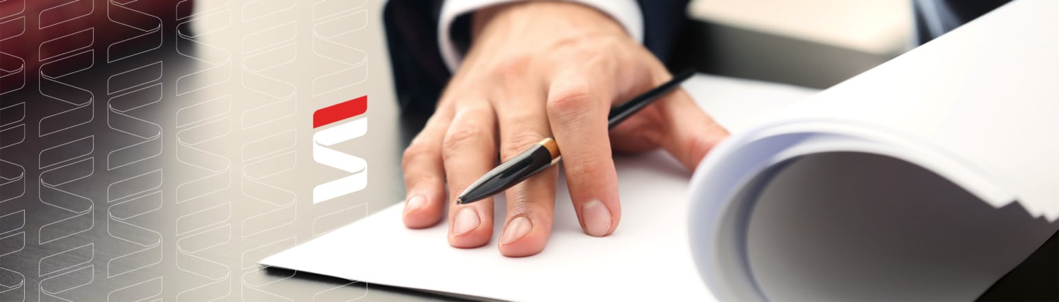 A close-up of a person's hand resting on a stack of papers, holding a black pen, with a desk and books in the background. Fraser Stryker logo icon repeating on the left side of the photo.