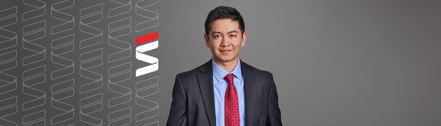 Photo of Daniel Ugarte, wearing a red tie, a blue shirt, and a grey jacket. Fraser Stryker logo icon repeating on the left side of the photo.