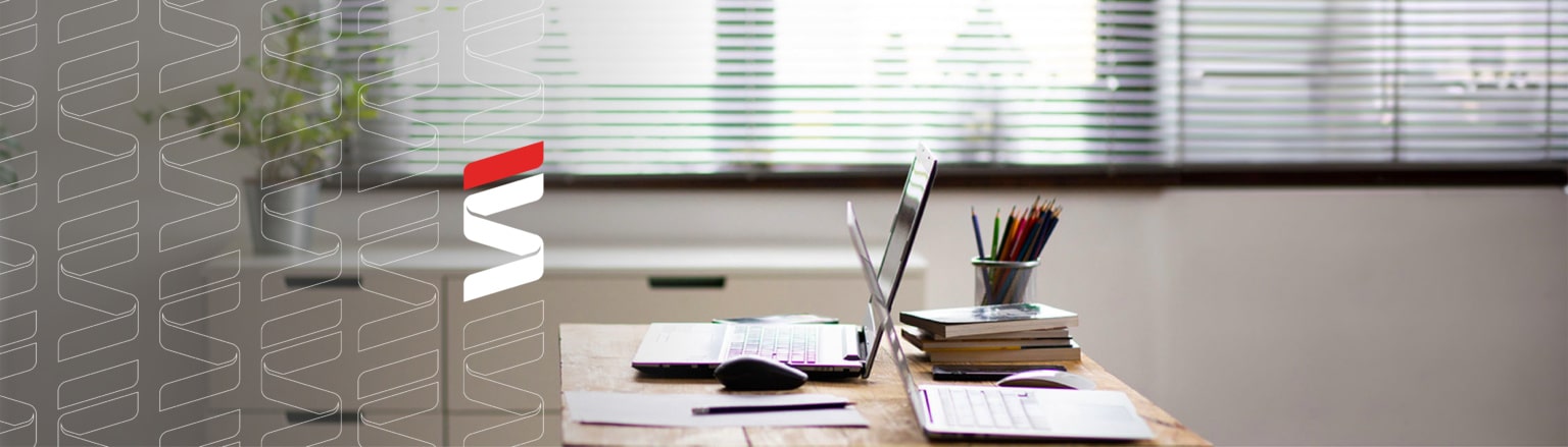 Photo of desk with two laptops, mouse, books, pens and notepad. Fraser Stryker logo icon repeating on the left side of the photo.