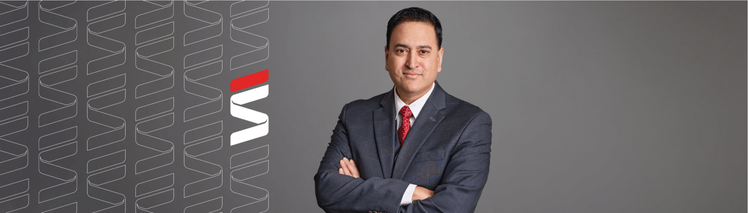 Amit Mukherjee, Fraser Stryker attorney, wearing a dark blue suit jacket and matching vest, with red tie and white shirt. Fraser Stryker logo icon repeating on the left side of the photo.