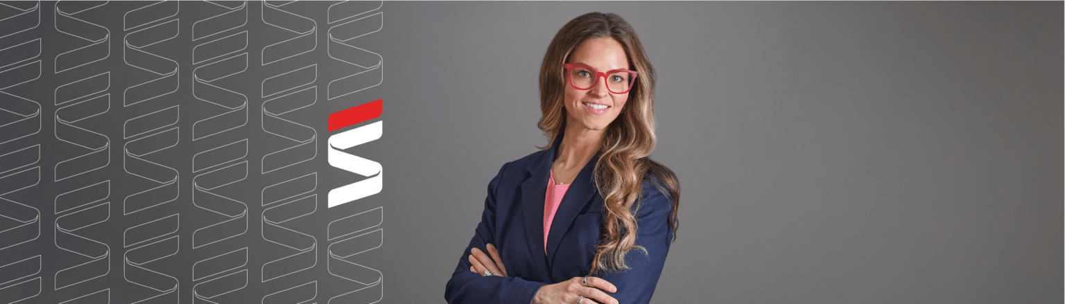 Olivia Norman, Fraser Stryker attorney, wearing a dark blue suit jacket and pink shirt. Fraser Stryker logo icon repeating on the left side of the photo.