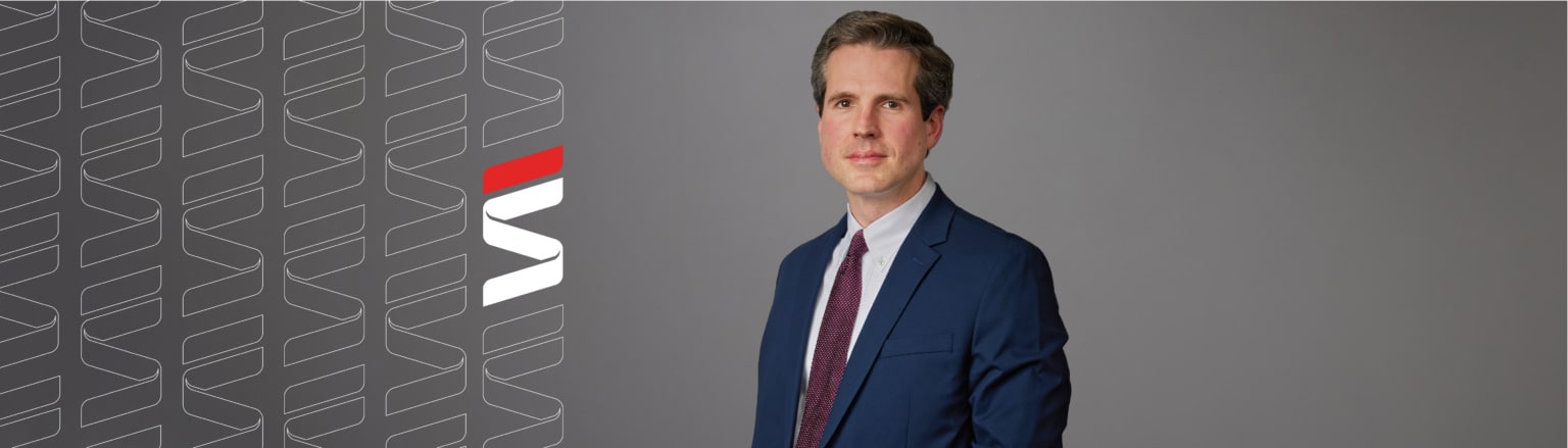 Mike Duffy, Fraser Stryker attorney, wearing a dark blue suit, white shirt and red tie. Fraser Stryker logo icon repeating on the left side of the photo.