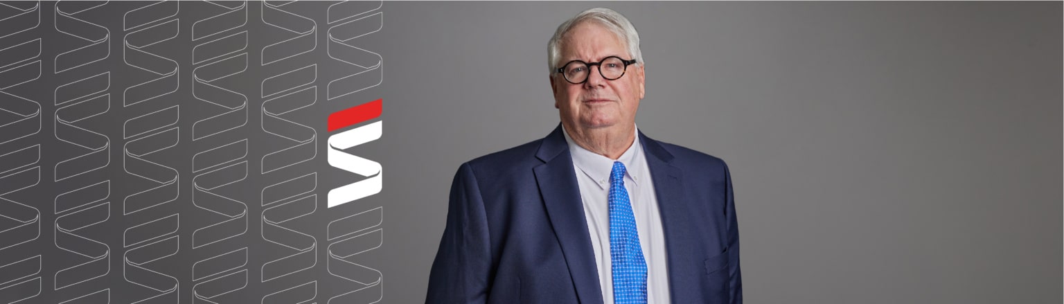Pat Barrett, Fraser Stryker attorney, wearing a dark blue suit, white shirt and a blue tie. Fraser Stryker logo icon repeating on the left side of the photo.
