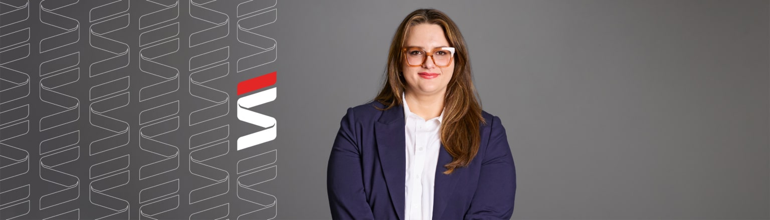 Megan Halbur, Fraser Stryker attorney, wearing a dark blue suit jacket and white shirt. Fraser Stryker logo pattern on the left side.