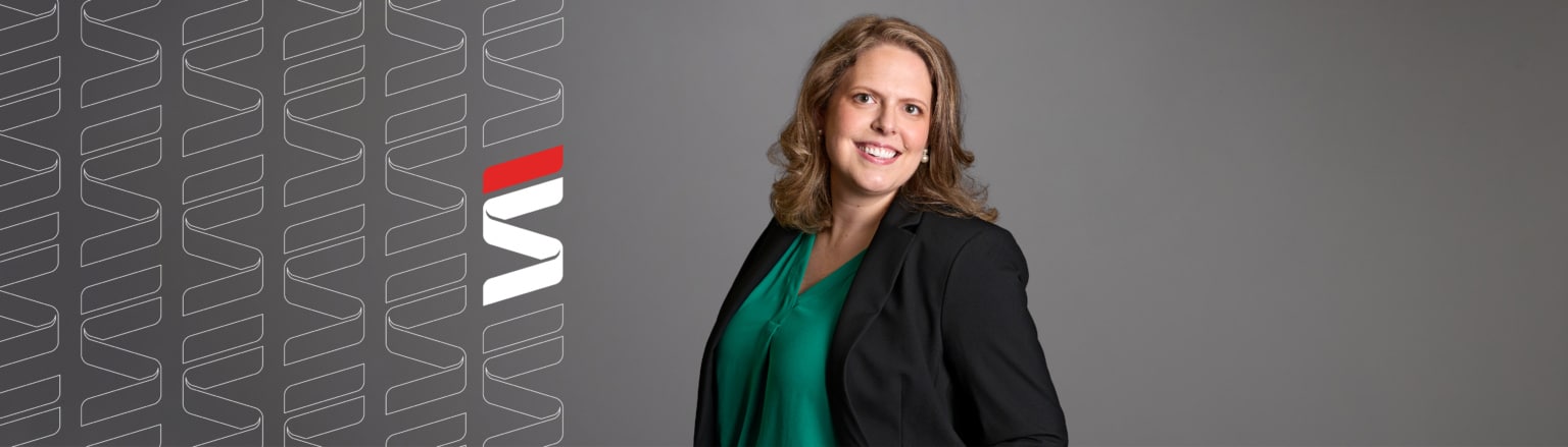 Meghan Bothe, Fraser Stryker attorney, wearing a black suit jacket and green top. Fraser Stryker logo pattern on the left side.