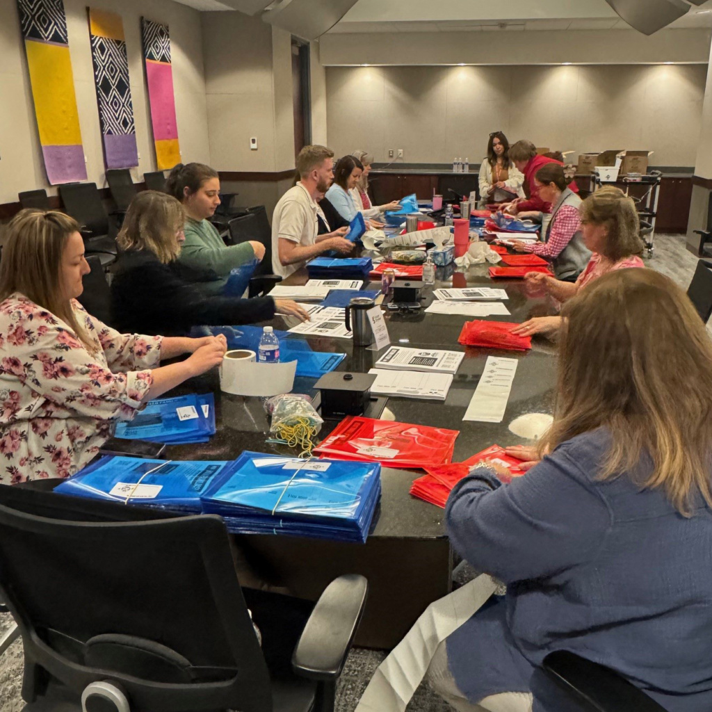 Group of people working in a conference room on folders for the DIBS for Kids nonprofit organization.