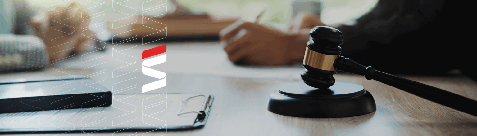 Photo of the hands of two individuals at a table, one signing a paper, one sitting with hands folded. Clip board, book, and gabel in the foreground. Fraser Stryker logo pattern on the left side.