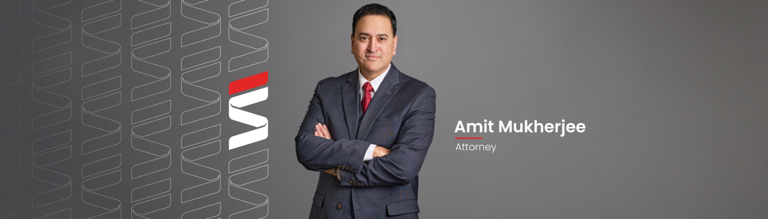 Amit Mukherjee, Fraser Stryker attorney, wearing a dark blue suit jacket and matching vest, with red tie and white shirt. Fraser Stryker logo icon repeating on the left side of the photo.