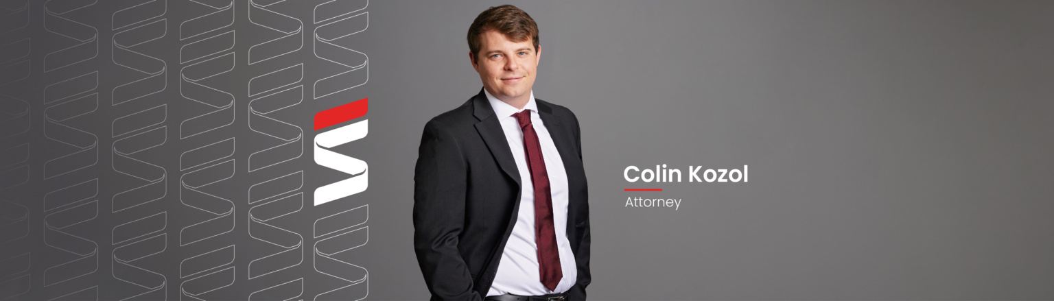 Attorney Colin Kozol standing in front of a grey background wearing a black suit, white shirt and maroon tie. Fraser Stryker logo repeating on right side.