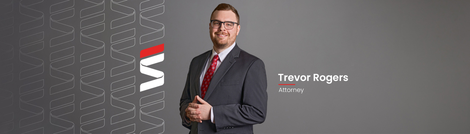 Trevor Rogers, Fraser Stryker attorney, wearing a dark grey suit, white shirt and red tie. Fraser Stryker logo icon repeating on the left side of the photo.