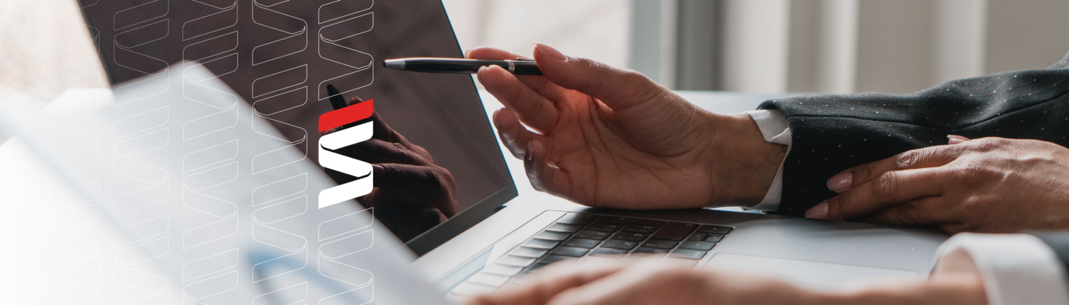 Two professionals engaged in a business discussion, one pointing with a pen while the other holds a document, with a laptop in the foreground. Fraser Stryker logo icon repeating on the left side of the photo.