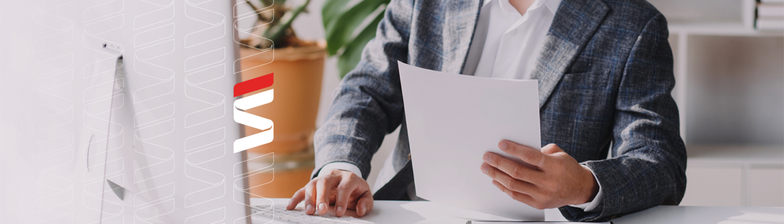 Photo of person looking at a piece of paper in front of a computer monitor. Fraser Stryker logo icon repeating on the left side of the photo.