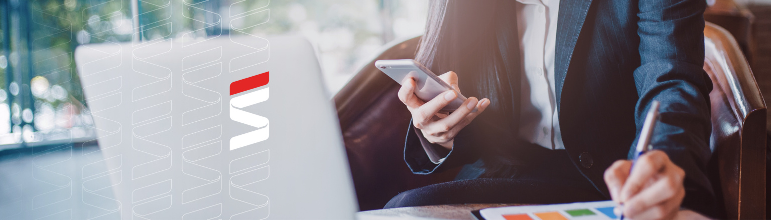 Close up photo of woman looking at phone while working on paperwork in front of a computer. Fraser Stryker logo icon repeating on the left side of the photo.
