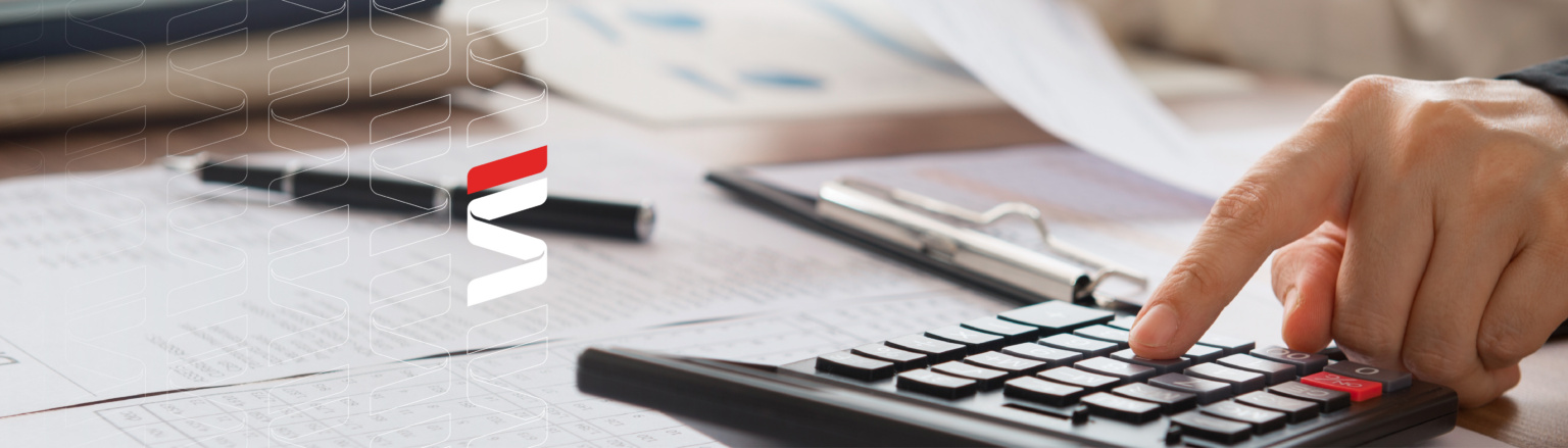Close up photo of person at desk typing on a calculator and looking at a piece of paper. Fraser Stryker logo icon repeating on to the left side of the photo.