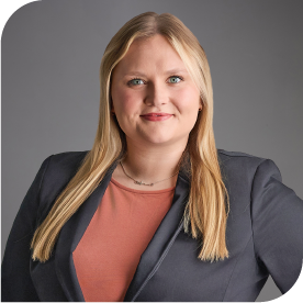 Anna Ulferts, Fraser Stryker Summer Associate, wearing a dark grey jacket and orange shirt